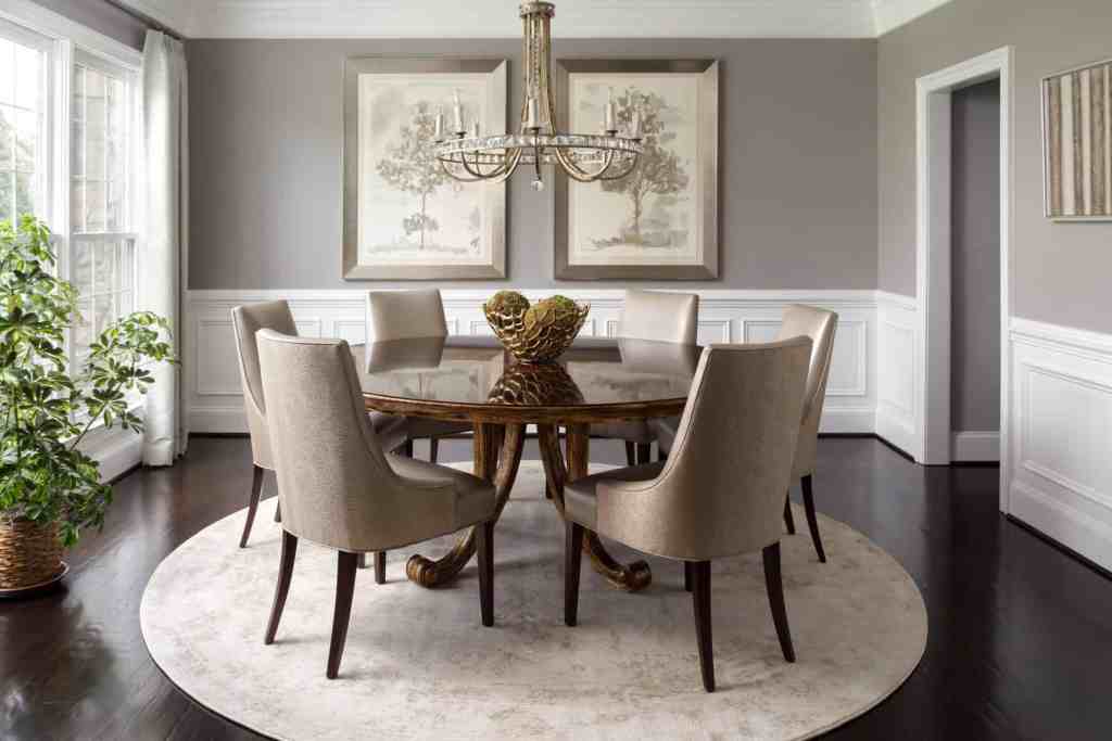 Chic dining area showcasing beige upholstered chairs, a round wooden table, and sophisticated wall art.