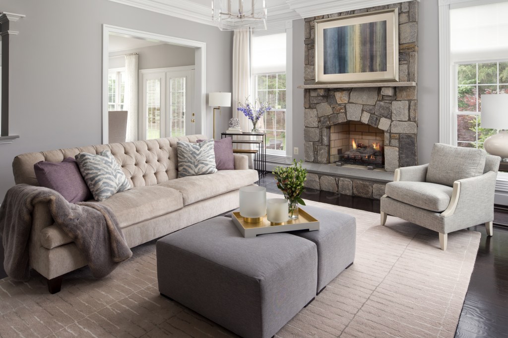 Spacious living room featuring a stone fireplace, neutral color palette, and stylish furniture.
