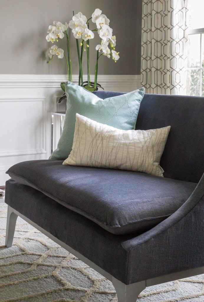Stylish dark fabric sofa paired with light-colored cushions and a lush orchid in a modern interior.