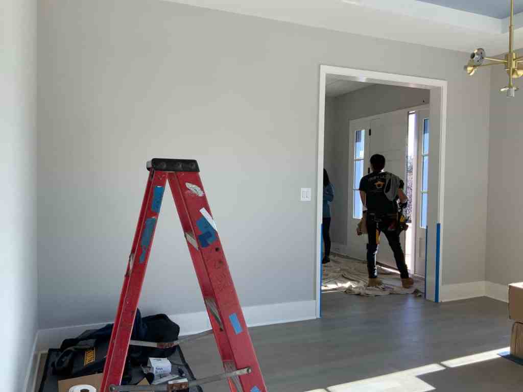 Construction workers installing trim in a bright, contemporary living space.