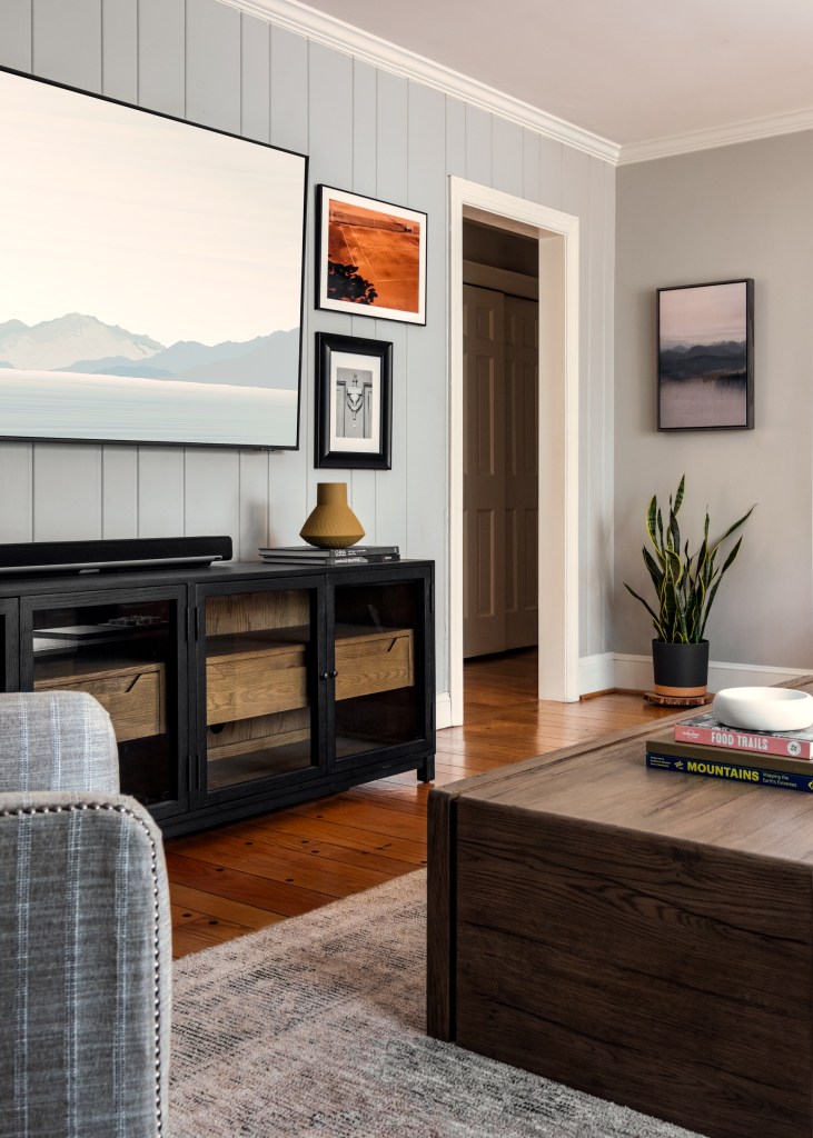 A framed photo of the family’s first home’s door knocker hangs beneath a vintage tennis image—quiet storytelling through art.