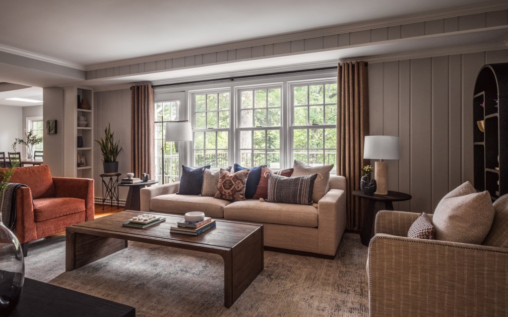 Oversized windows frame the lush streamside view, making nature the room’s backdrop.
