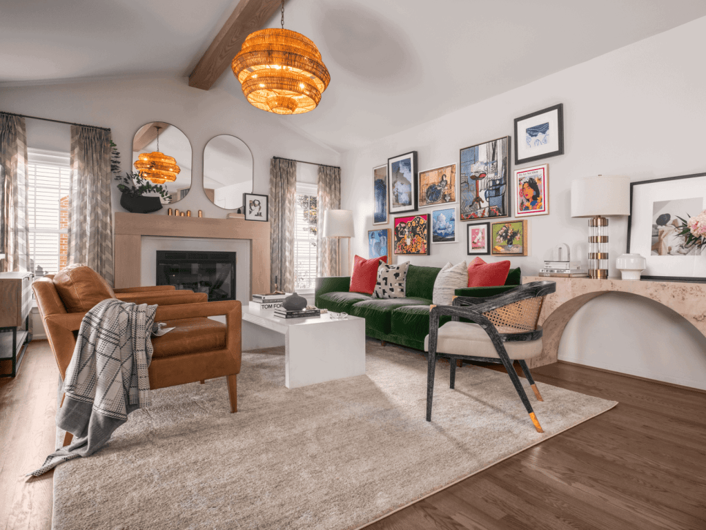 Modern colonial family room featuring layered art, a green velvet sofa, and warm leather seating.
